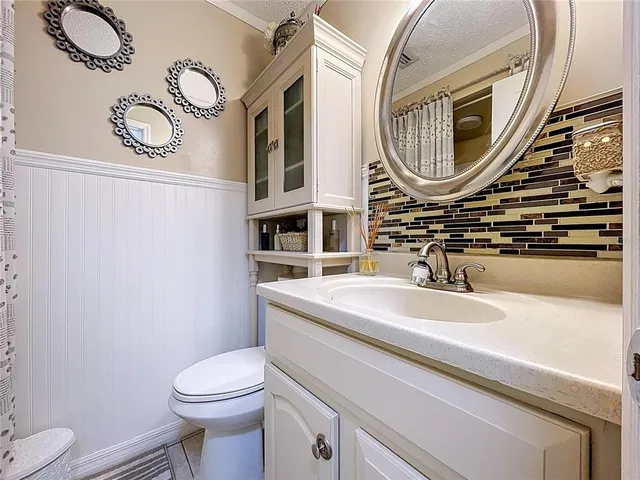 a bathroom with a granite countertop sink a toilet a mirror and shower