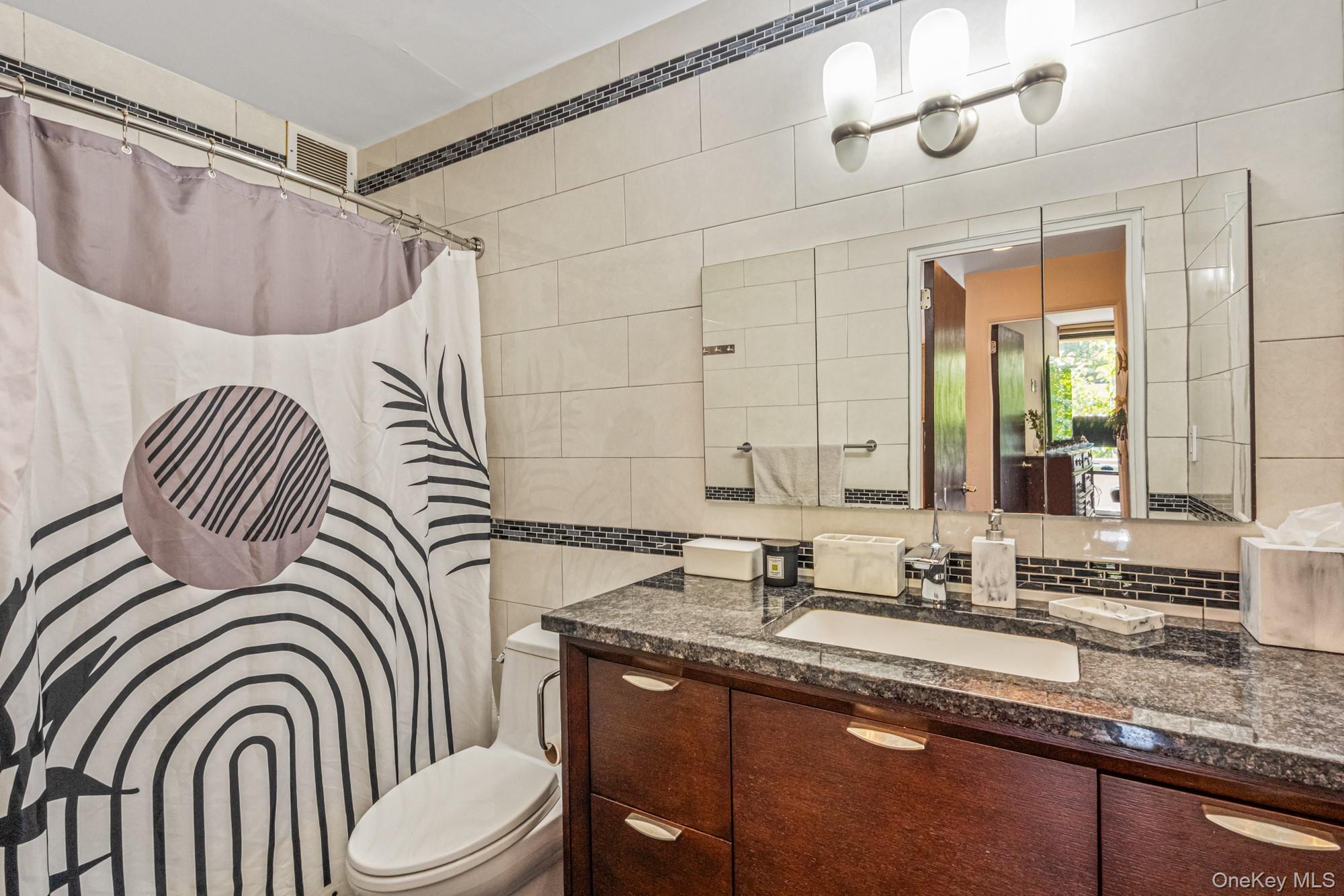 168-01 12th Avenue, Unit 3A Queens, NY 11357 - Photo 19 of 22 a bathroom with a sink a mirror a toilet and a window