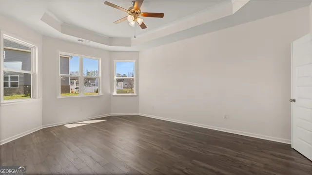 a view of an empty room with window and wooden floor