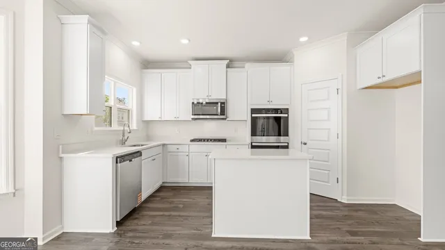 a kitchen with stainless steel appliances granite countertop a stove top oven a sink and a refrigerator