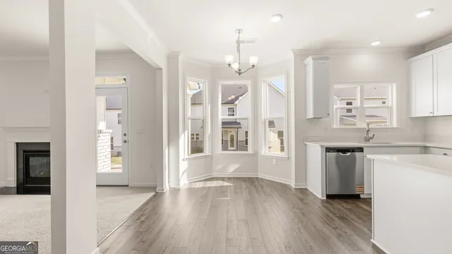 a kitchen with stainless steel appliances granite countertop a refrigerator a sink dishwasher a oven and white cabinets with wooden floor