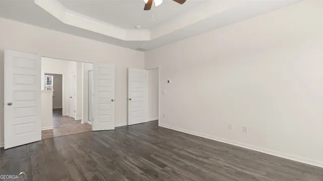 an empty room with wooden floor chandelier fan and windows