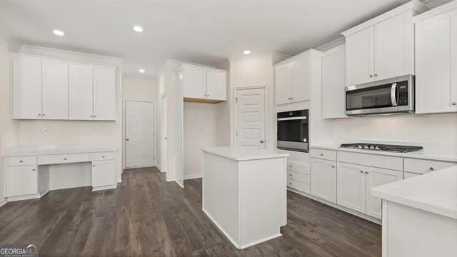 a kitchen with stainless steel appliances a stove top oven a sink a refrigerator white cabinets and wooden floor