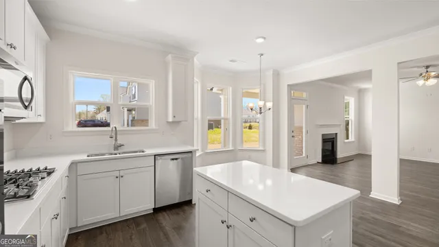 a kitchen with a sink dishwasher and white cabinets with wooden floor