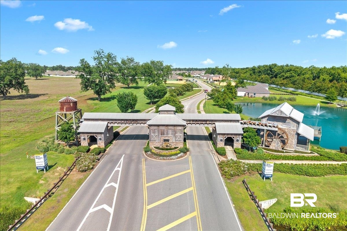 23641 Unbridled Loop Daphne, AL 36526 - Photo 33 of 40 Gated entry featuring a water mill structure with an oversized water wheel, a decorative water tower, and a central roundabout with a fountain