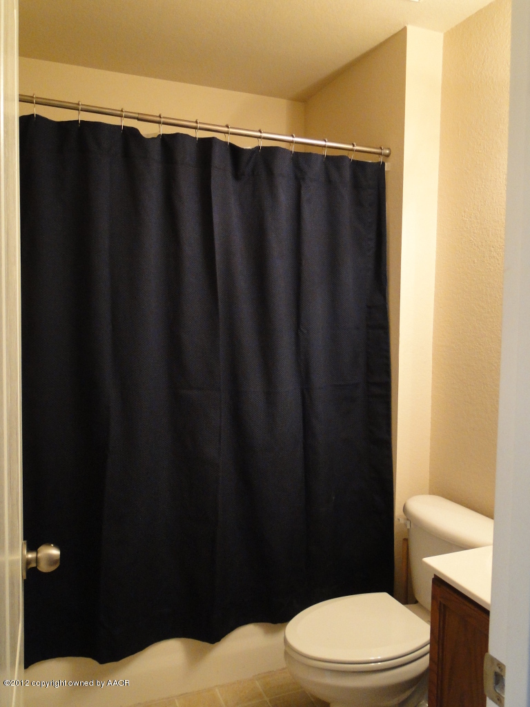 4805 Nimbus Lane Amarillo, TX 79110 - Photo 13 of 15 a bathroom with a shower curtain and a toilet