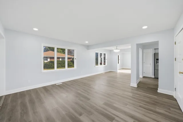 a view of an empty room with wooden floor and a window