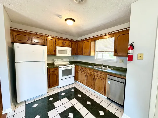 a kitchen with granite countertop stainless steel appliances a stove a sink and a refrigerator