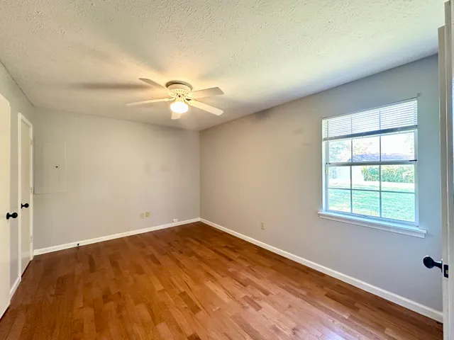 an empty room with a window and a fan