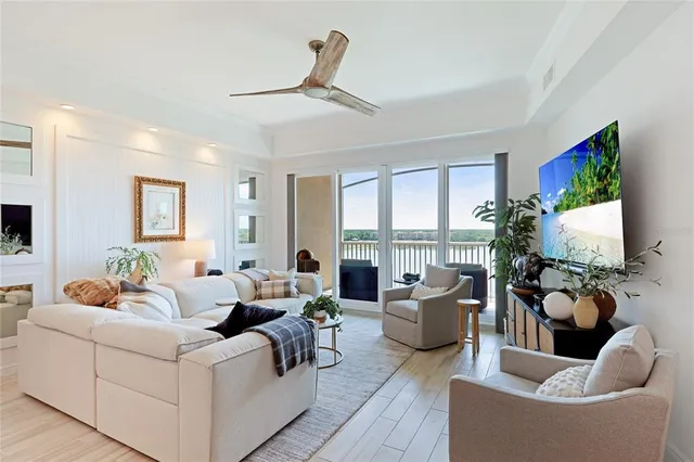 a living room with furniture ceiling fan and a large window