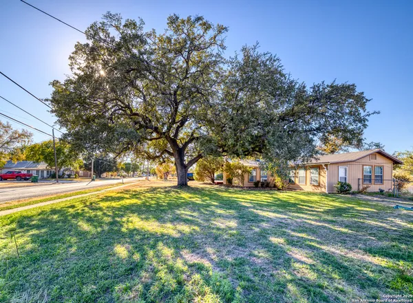 a view of a house with a big yard and large trees