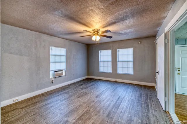 a view of an empty room with window and wooden floor