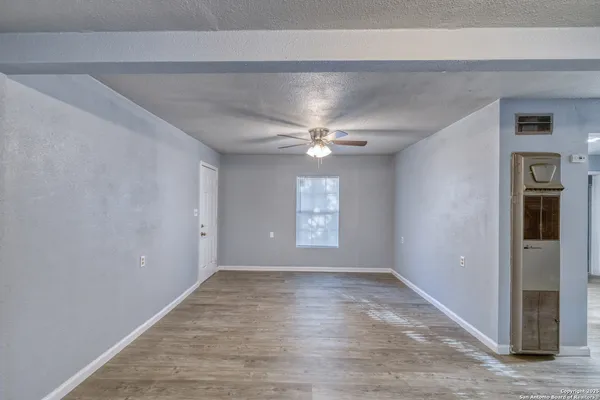 a view of an empty room with wooden floor and a window