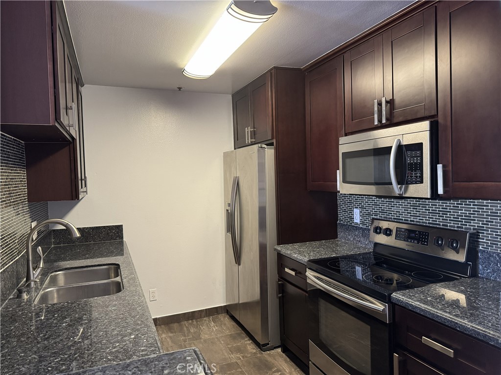 222 South Central Avenue, Unit 214 Los Angeles, CA 90012 - Photo 3 of 21 a kitchen with granite countertop wooden cabinets and stainless steel appliances