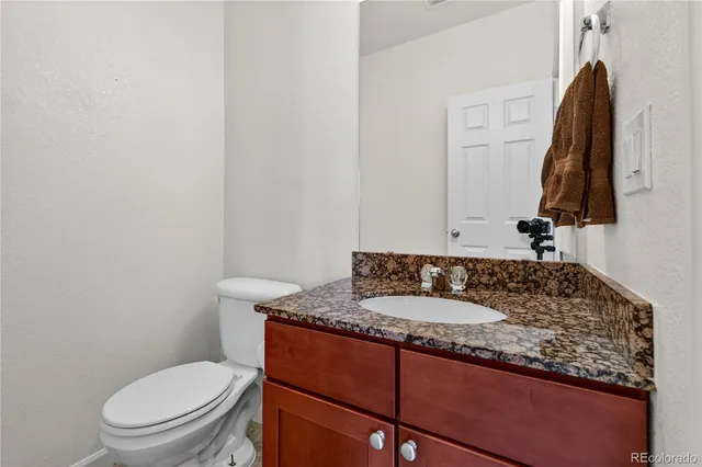 a bathroom with a granite countertop sink and a toilet