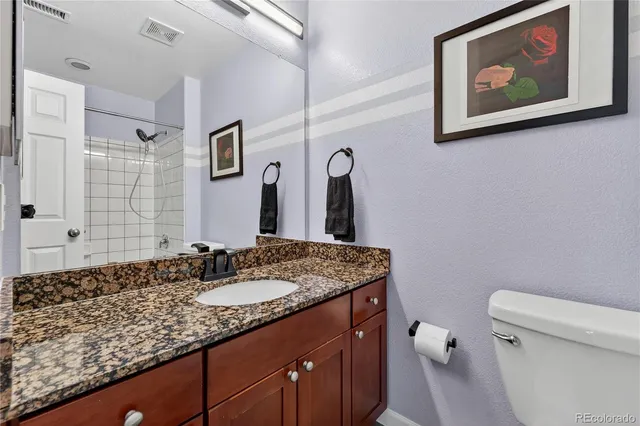 a bathroom with a granite countertop sink mirror vanity and toilet