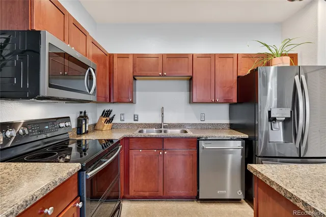 a kitchen with stainless steel appliances granite countertop a refrigerator a stove a sink and a microwave