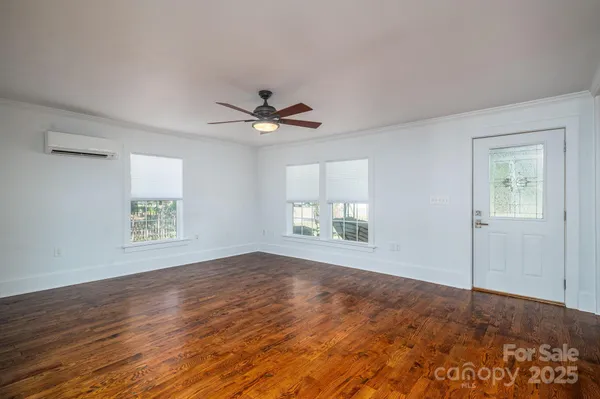 a view of an empty room with a window and wooden floor