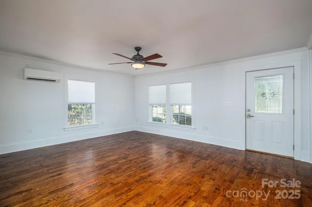 a view of an empty room with a window and wooden floor