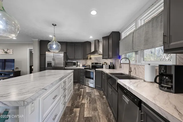 a kitchen with stainless steel appliances kitchen island granite countertop a sink stove cabinets and wooden floor