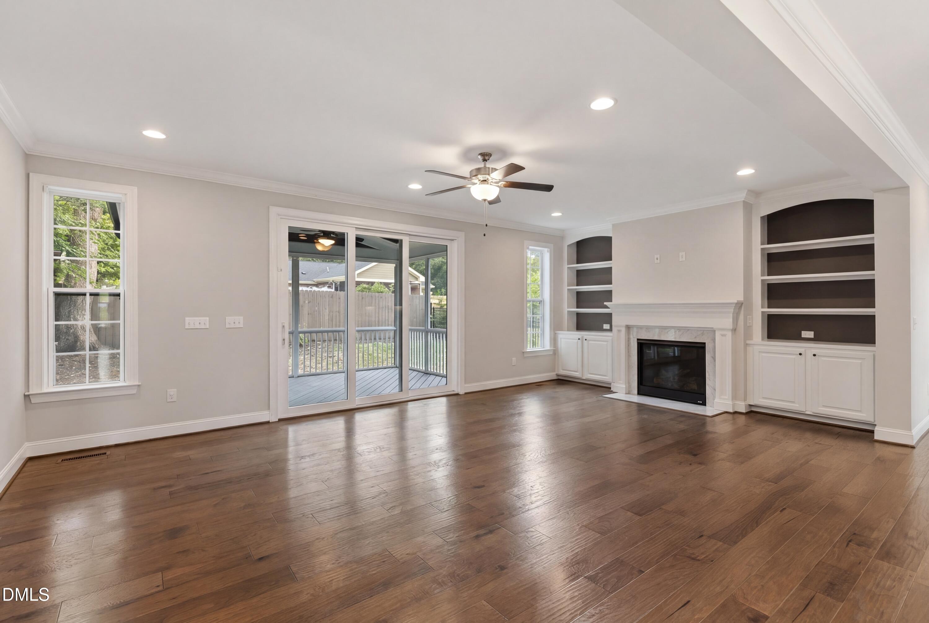 7421 Stonehenge Farm Lane Raleigh, NC 27613 - Photo 5 of 48 an empty room with wooden floor fireplace and windows
