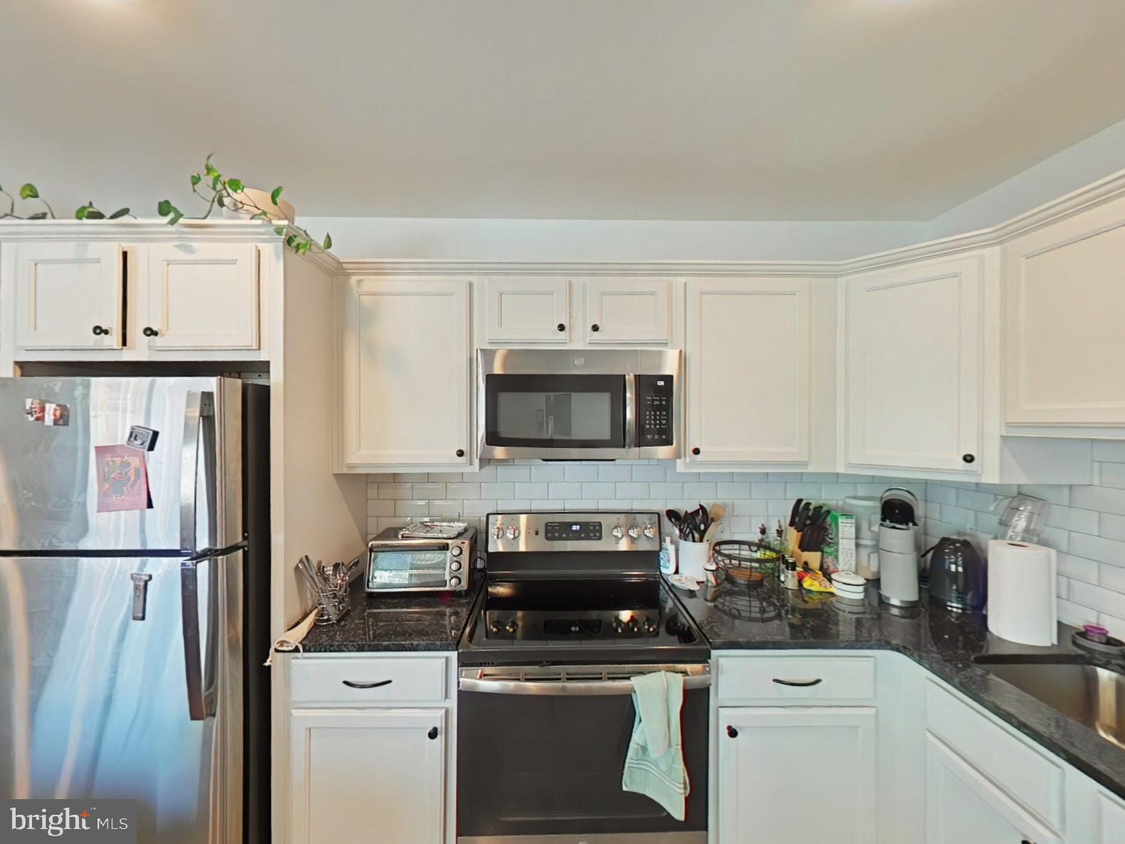 5420 Ridge Avenue, Unit 308 Philadelphia, PA 19128 - Photo 4 of 9 a kitchen with stainless steel appliances granite countertop a refrigerator a stove a sink and white cabinets