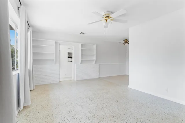 an empty room with fan and windows
