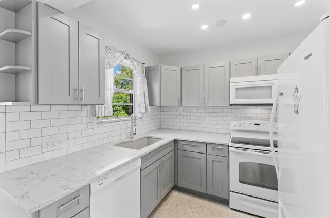 a kitchen with granite countertop white cabinets sink and stainless steel appliances