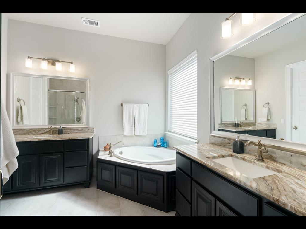 191 Daniel Drive Van Alstyne, TX 75495 - Photo 14 of 32 a bathroom with a double vanity sink a large mirror and a bathtub