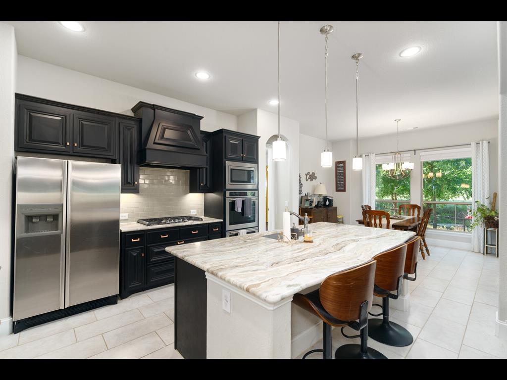 191 Daniel Drive Van Alstyne, TX 75495 - Photo 9 of 32 a kitchen with stainless steel appliances kitchen island granite countertop a table chairs stove and refrigerator