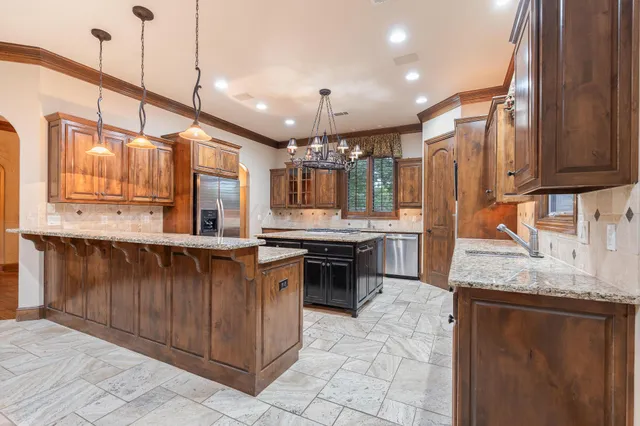 a kitchen with stainless steel appliances granite countertop a stove a sink and a refrigerator