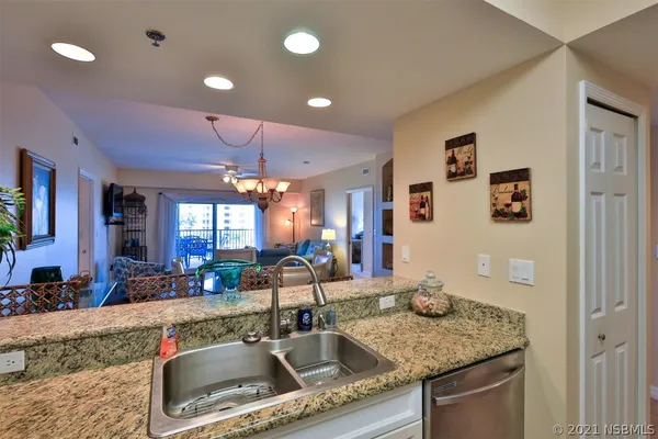 a kitchen with a sink a counter top space and living room view
