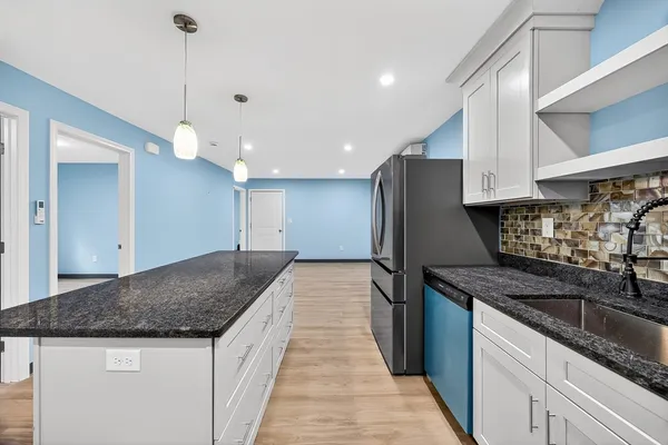 a kitchen with stainless steel appliances granite countertop a sink a stove and a wooden cabinets