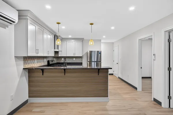 a large white kitchen with kitchen island a sink stainless steel appliances and cabinets
