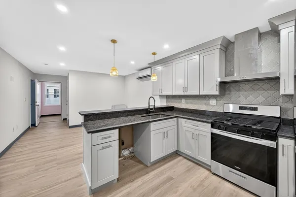 a kitchen with granite countertop a stove and white cabinets