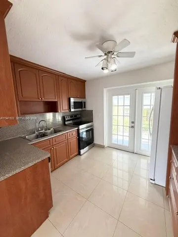 a large kitchen with stainless steel appliances granite countertop a stove a sink dishwasher a refrigerator and cabinets with wooden floor