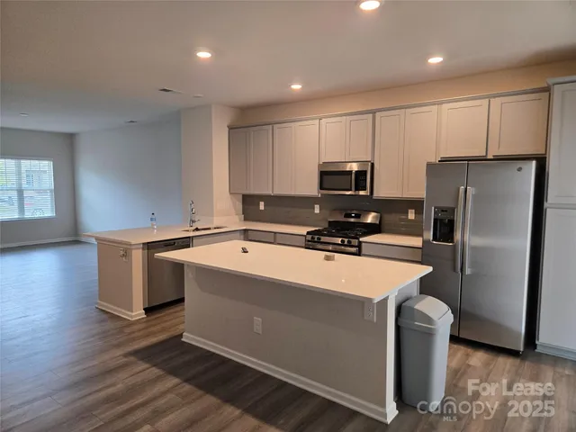 a kitchen with stainless steel appliances granite countertop a refrigerator a stove top oven a sink and dishwasher