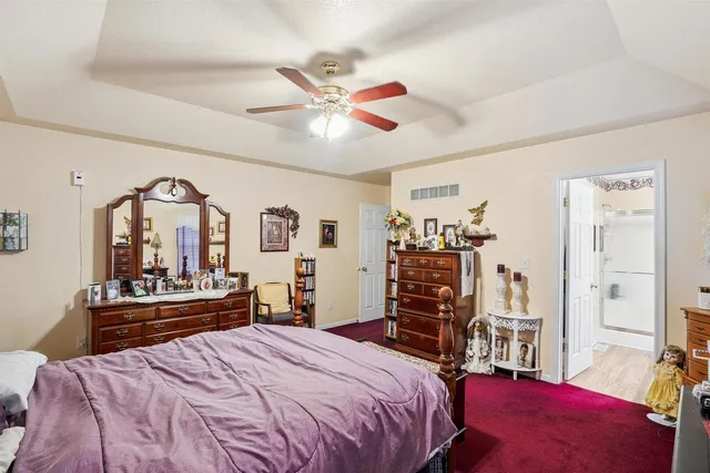 a bedroom with a bed and dresser with wooden floor