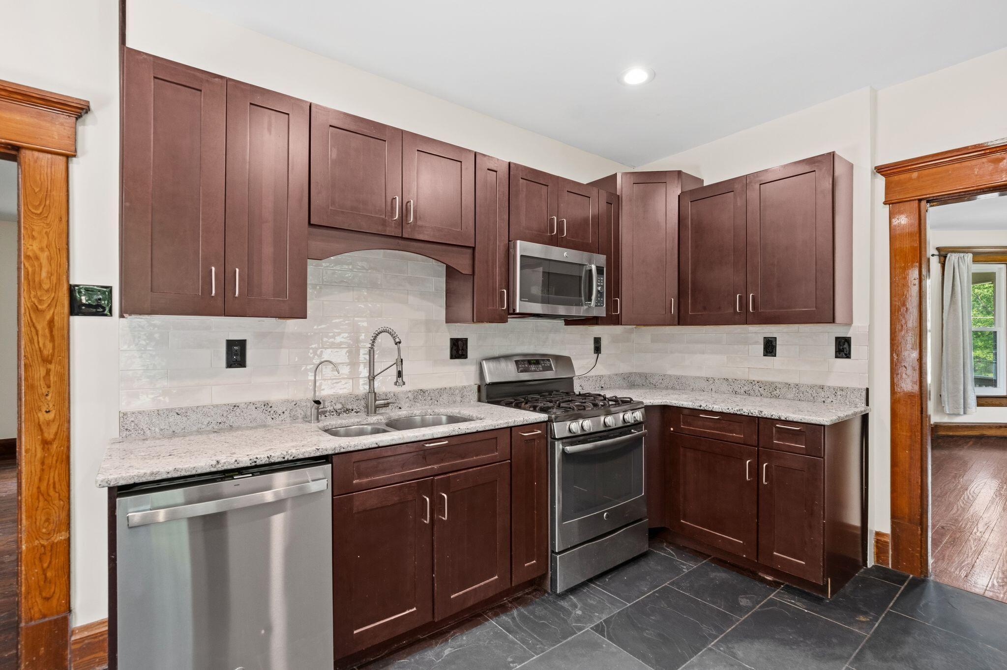 107 Price Road Columbus, OH 43230 - Photo 9 of 51 Kitchen featuring dark wood cabinetry, light-colored speckled countertops, and a white tile backsplash