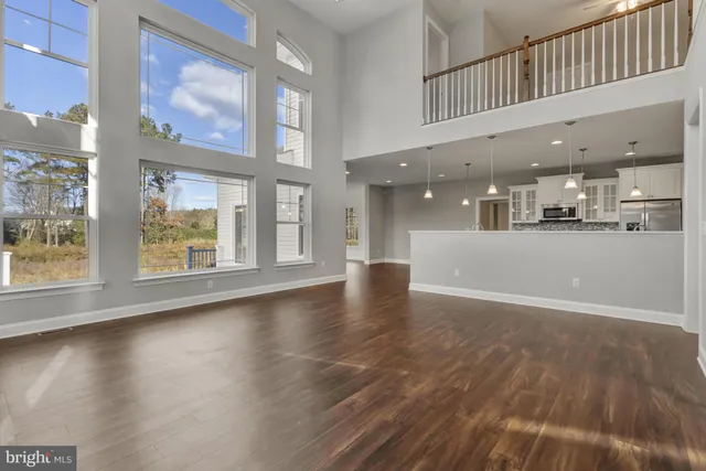an empty room with wooden floor and windows with curtains