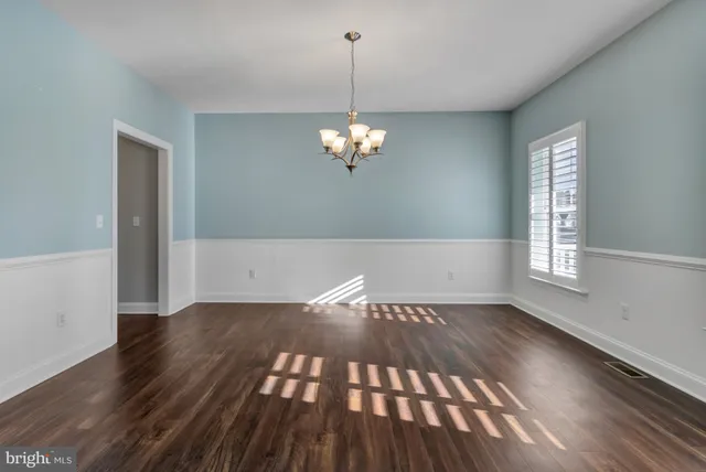 a kitchen with stainless steel appliances granite countertop a refrigerator a sink dishwasher a stove and white cabinets with wooden floor