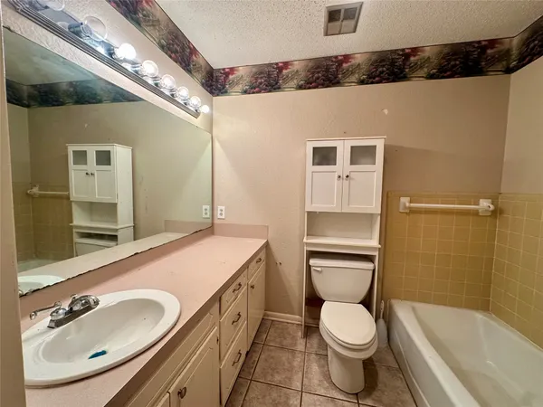 a bathroom with a granite countertop toilet sink and mirror