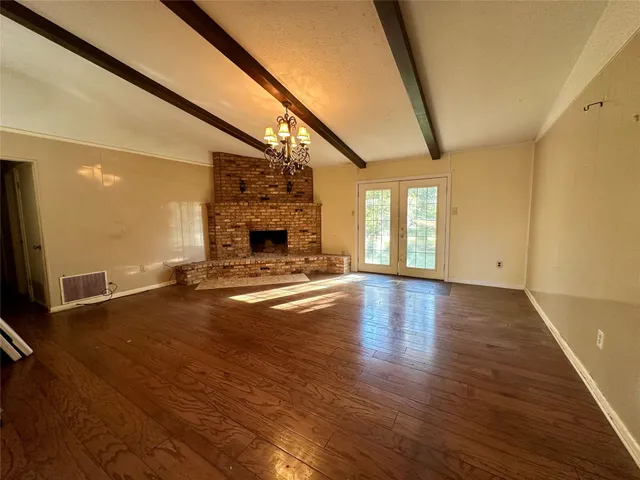 a view of empty room with wooden floor and fireplace