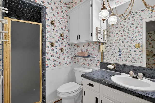 a bathroom with a granite countertop double vanity sink mirror and toilet