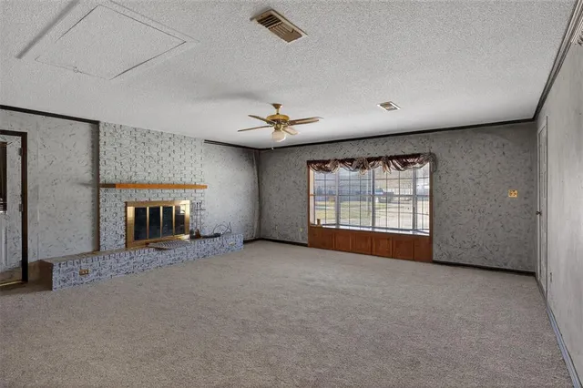 an empty room with windows and fireplace