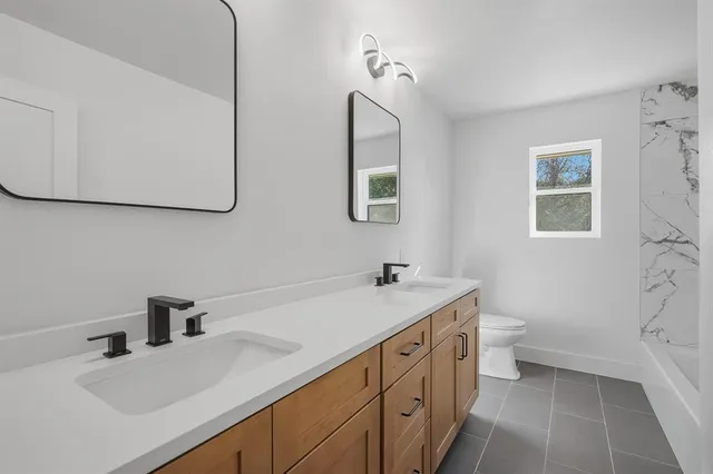 a bathroom with a double vanity sink mirror and bathtub