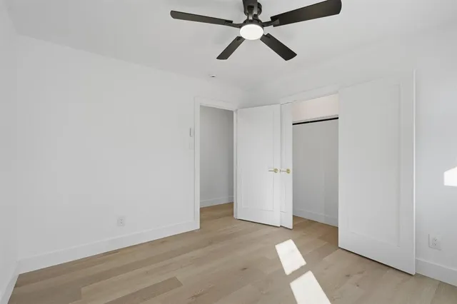 an empty room with wooden floor fan and windows