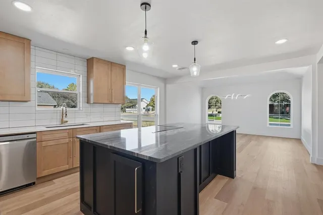 a kitchen with center island a sink dishwasher a stove and a refrigerator with wooden floor