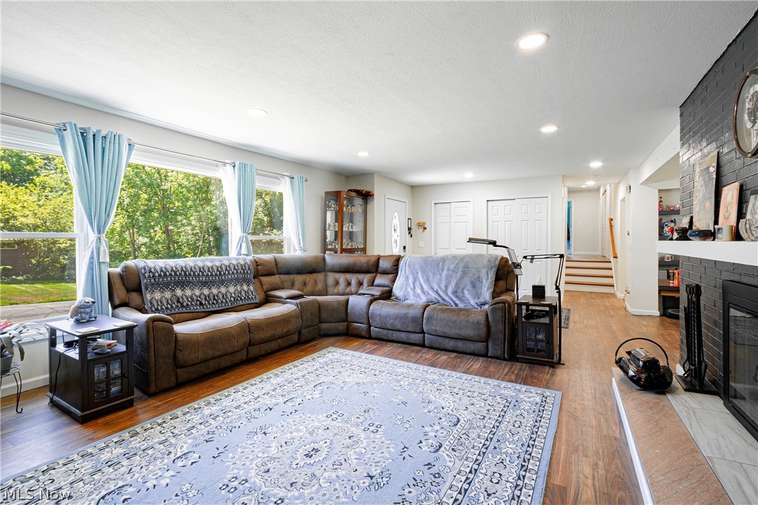 Living room with hardwood / wood-style flooring, a brick fireplace, and a textured ceiling