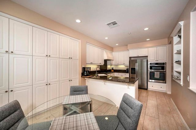 a kitchen with stainless steel appliances granite countertop a refrigerator oven a sink dishwasher and white cabinets with wooden floor